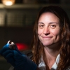 Woman holding human bone fragment in lab.